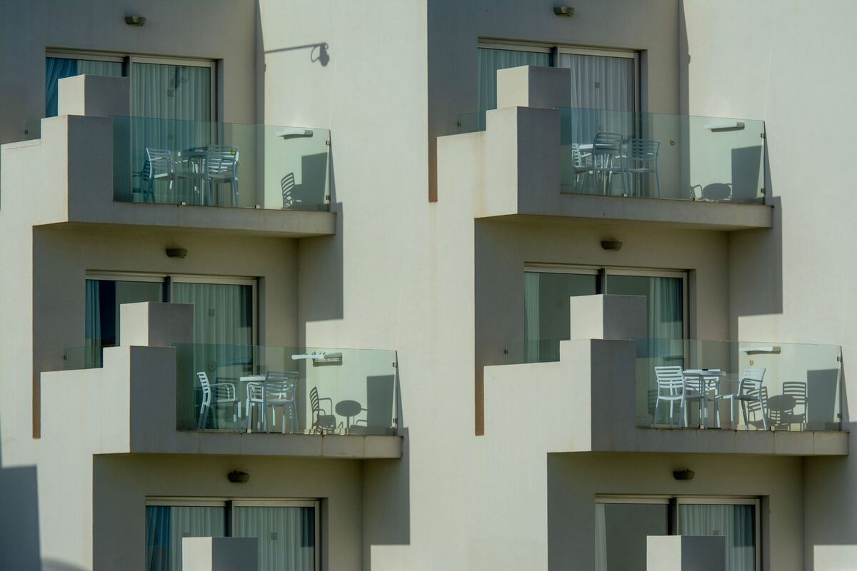 Apartment balconies with glass rails and patio furniture