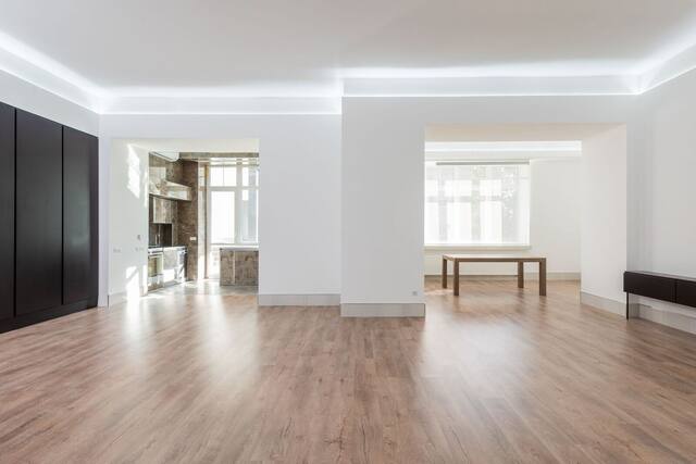 Empty apartment living room with wood floors and tall windows