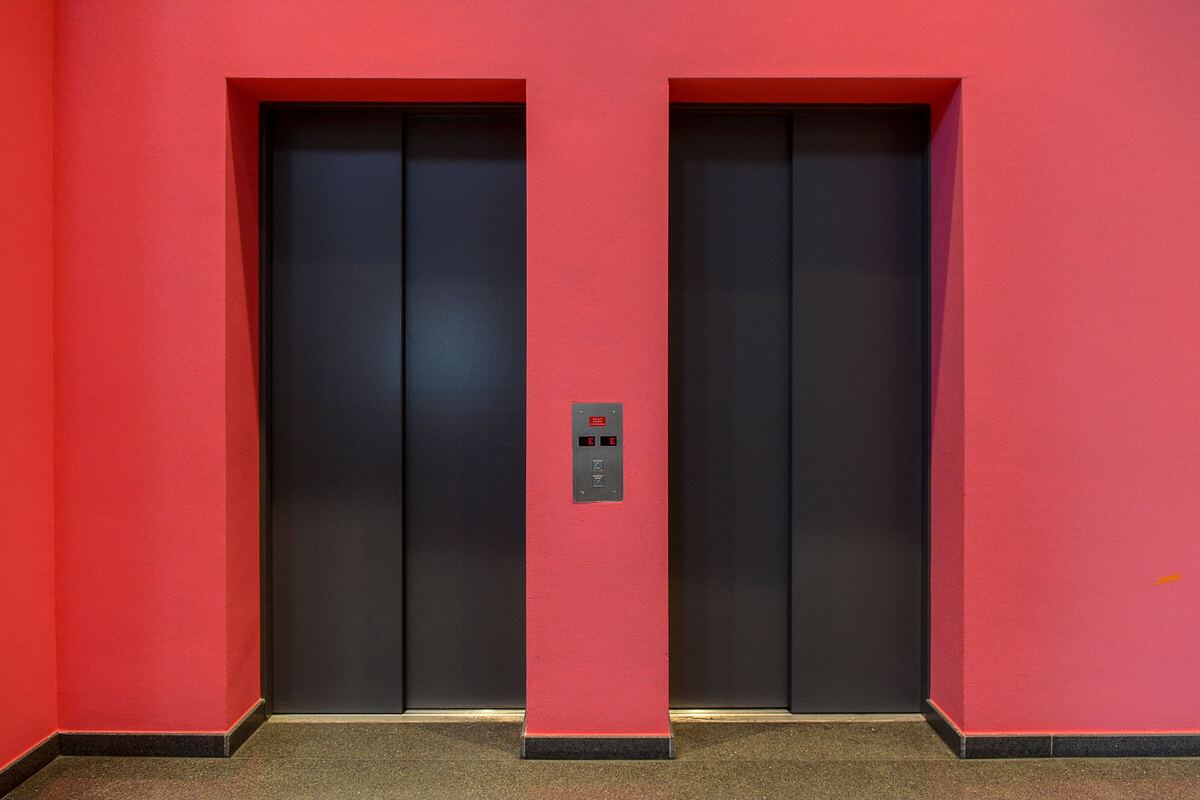 Two elevator doors set into a red lobby wall