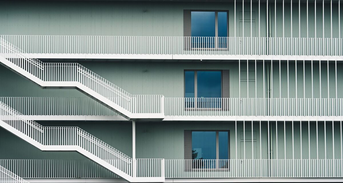 Exterior stair flight climbing a white apartment building