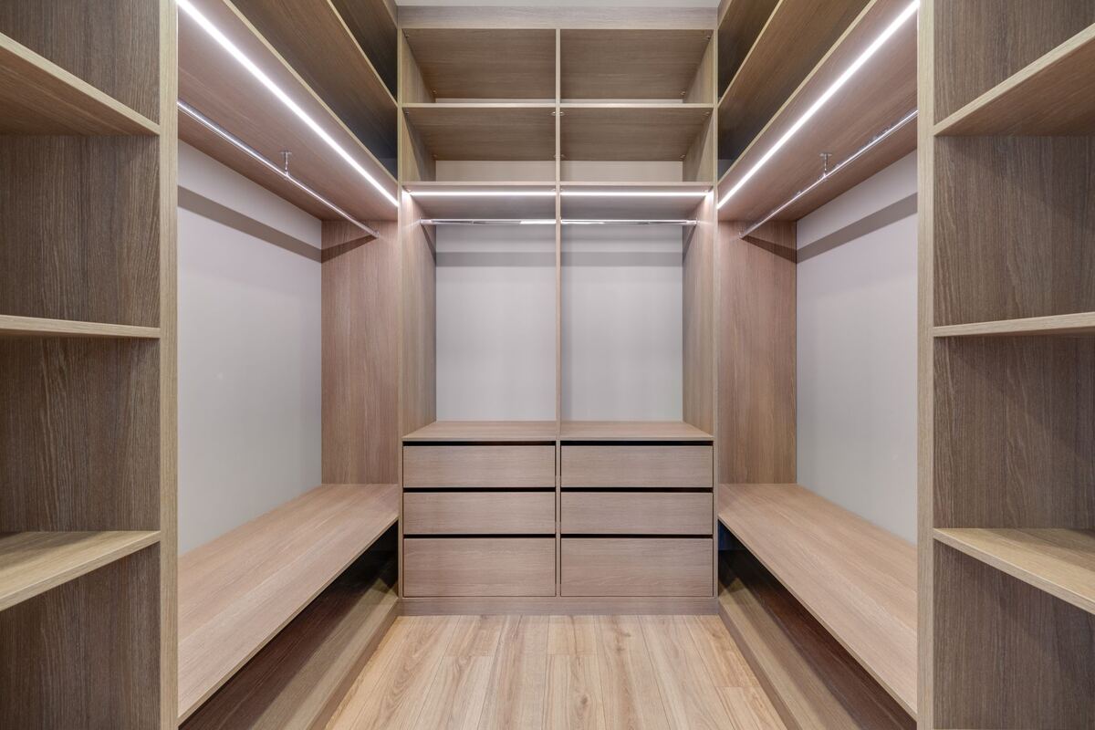 Empty walk-in closet with wood shelving and drawers
