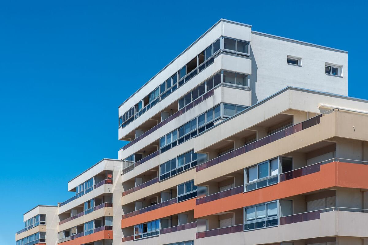 White mid-rise apartment building against a clear sky