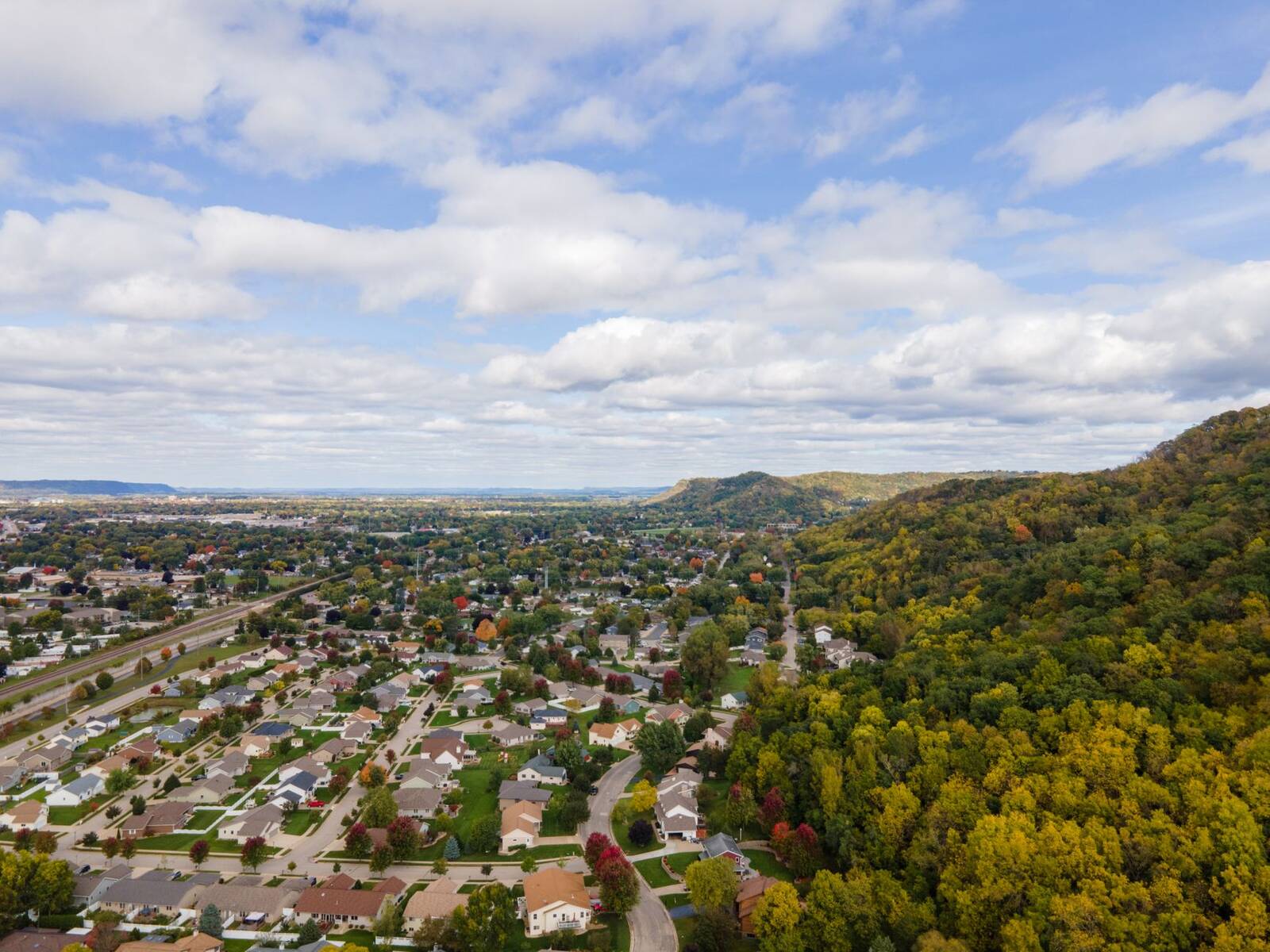 Aerial view of a wooded suburban neighborhood below low hills